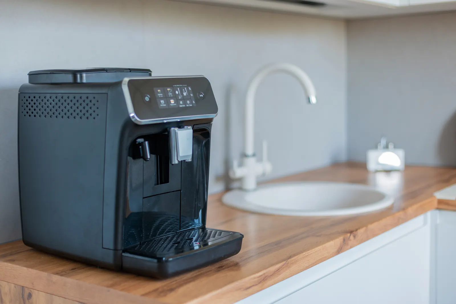 Black automatic espresso machine on a wooden kitchen counter
