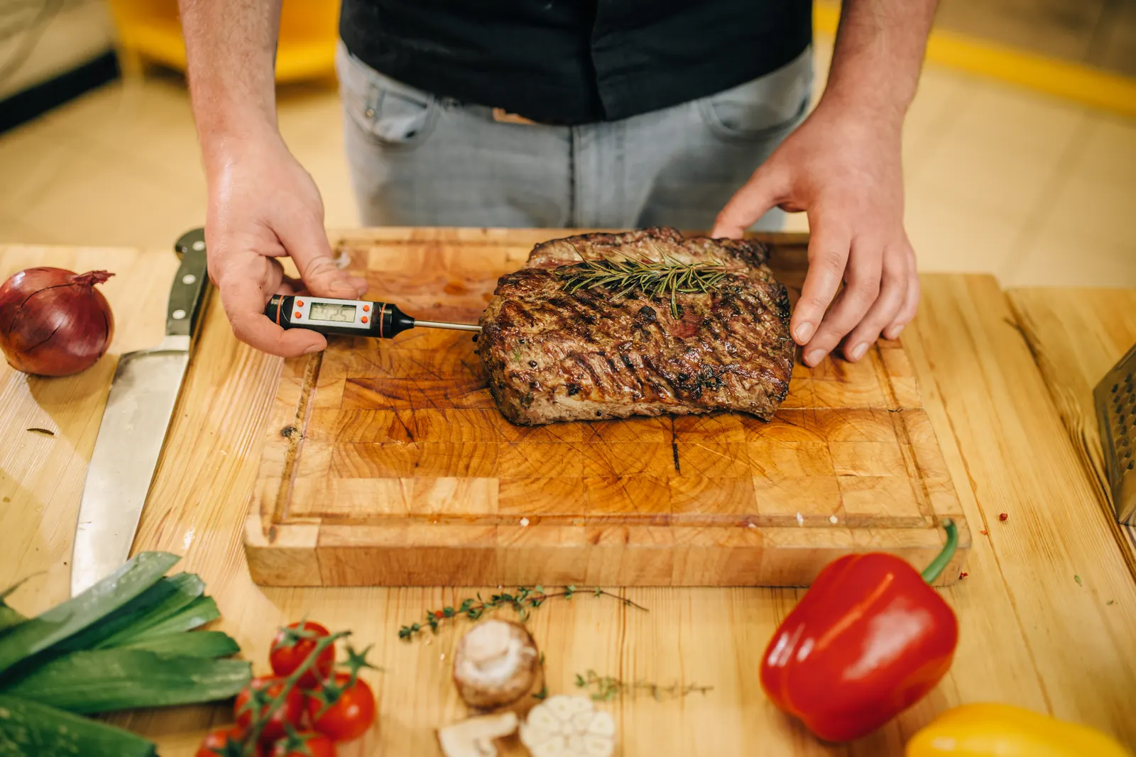 Probe thermometer checking the temperature of a roast on a cutting board